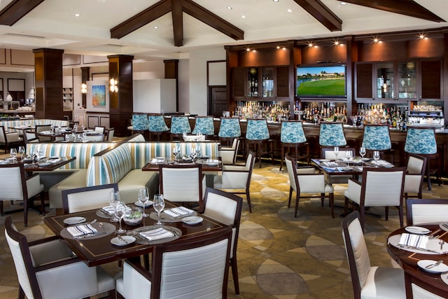 dining space with bar area and beamed ceiling