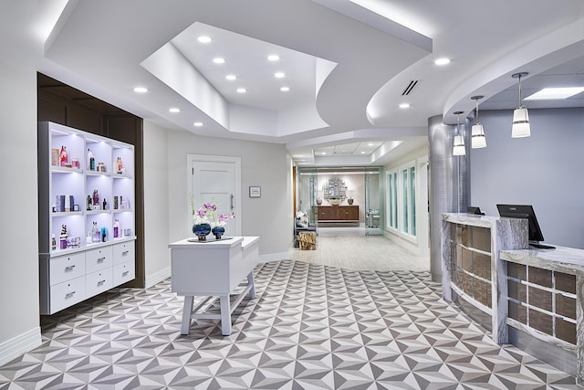 home office featuring a tray ceiling and bar