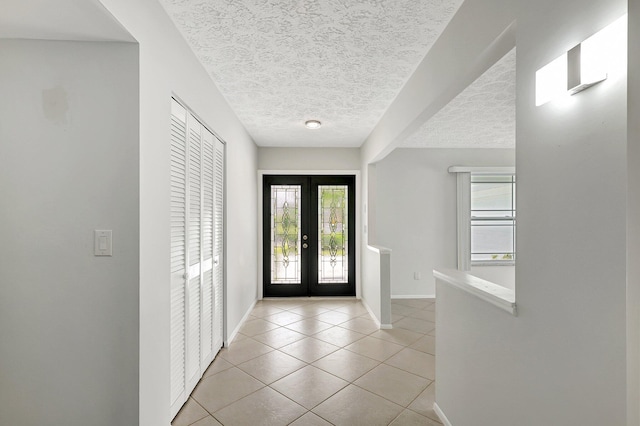 entrance foyer featuring a textured ceiling, french doors, light tile patterned flooring, and baseboards