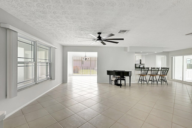 empty room featuring ceiling fan with notable chandelier, a textured ceiling, and light tile patterned floors