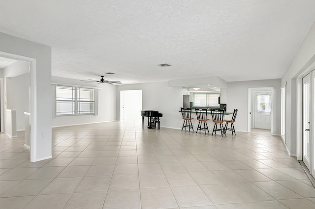 dining space with ceiling fan, a textured ceiling, and light tile patterned flooring