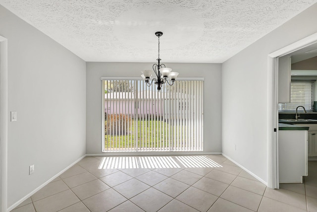 unfurnished dining area featuring a chandelier, a textured ceiling, light tile patterned floors, and sink