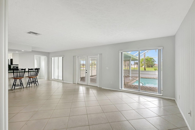 spare room with a healthy amount of sunlight, visible vents, french doors, and light tile patterned flooring