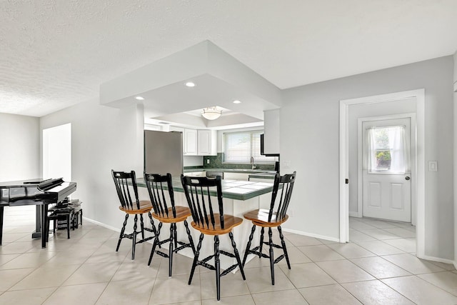 dining area featuring a textured ceiling, a healthy amount of sunlight, sink, and light tile patterned floors