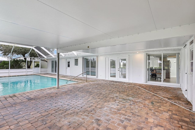 pool featuring glass enclosure, french doors, and a patio