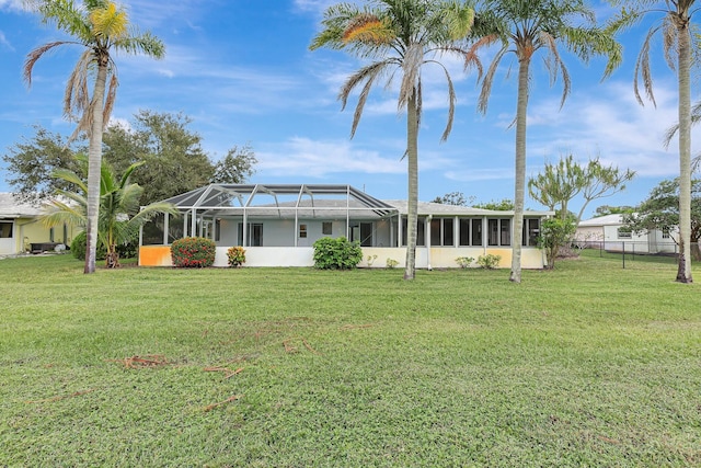 back of property featuring a yard, fence, and glass enclosure