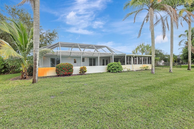 rear view of property featuring a yard, a lanai, and fence