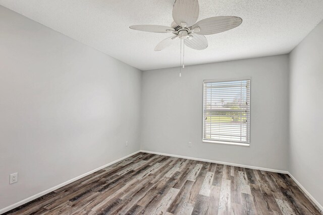 empty room featuring a textured ceiling, dark wood-type flooring, and ceiling fan