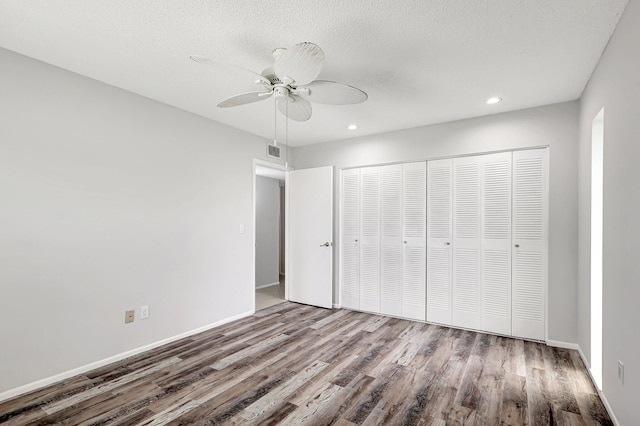 unfurnished bedroom featuring a closet, hardwood / wood-style floors, ceiling fan, and a textured ceiling