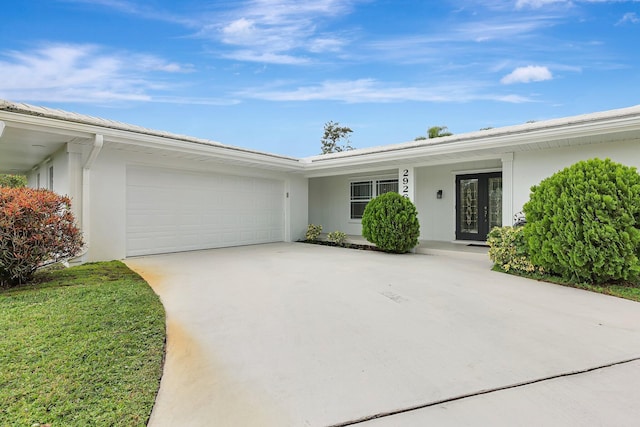 ranch-style home with an attached garage, stucco siding, driveway, and french doors