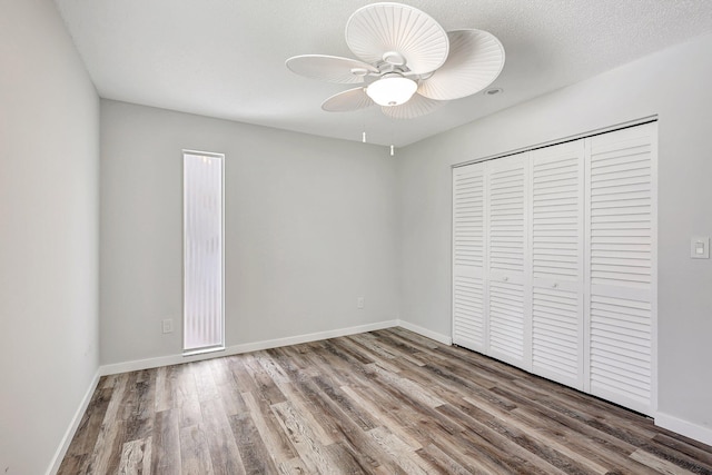 unfurnished bedroom with hardwood / wood-style floors, ceiling fan, a textured ceiling, and a closet