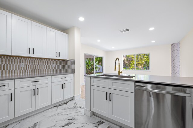 kitchen featuring tasteful backsplash, sink, white cabinetry, and stainless steel dishwasher