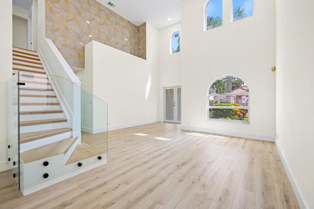 unfurnished living room with light hardwood / wood-style flooring and a towering ceiling