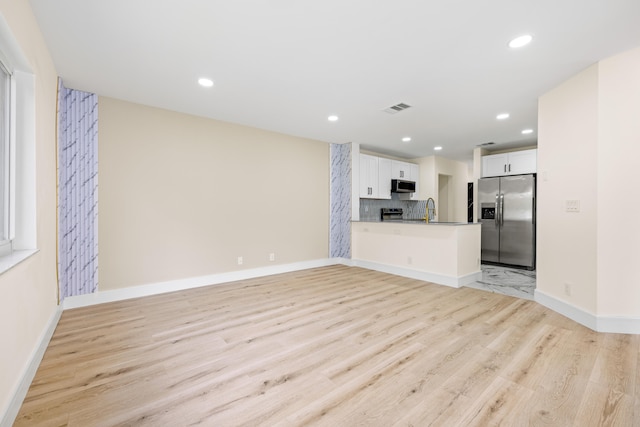 unfurnished living room featuring light hardwood / wood-style floors and sink