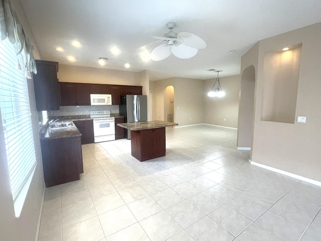 kitchen featuring a center island, white appliances, ceiling fan with notable chandelier, sink, and light tile patterned floors