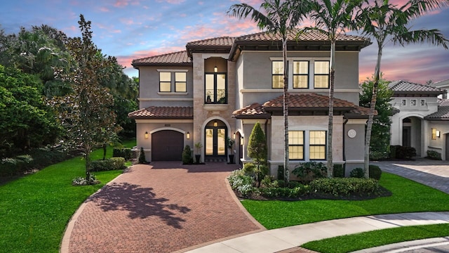 mediterranean / spanish-style house featuring a garage, french doors, and a lawn