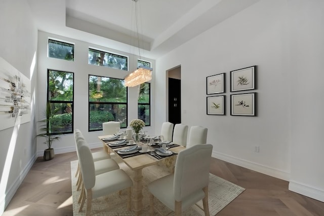 dining area featuring a tray ceiling, a towering ceiling, and parquet flooring