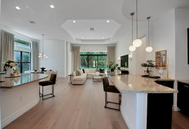 kitchen with pendant lighting, a kitchen bar, and light stone counters