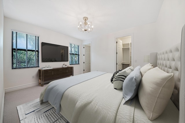 bedroom featuring light carpet, a spacious closet, a notable chandelier, and multiple windows
