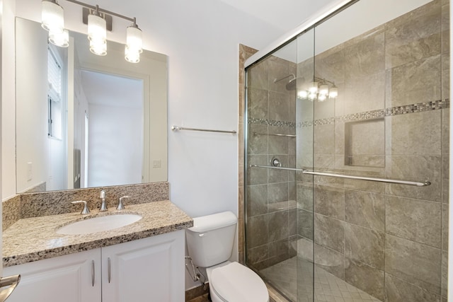 bathroom with a stall shower, vanity, and toilet