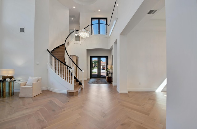 foyer entrance with a towering ceiling, light parquet flooring, and french doors