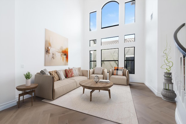 living room featuring a high ceiling, baseboards, and a healthy amount of sunlight