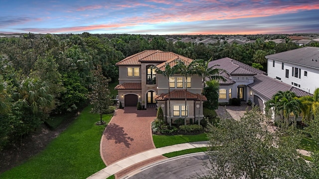 mediterranean / spanish house featuring a yard, stucco siding, a tile roof, and decorative driveway