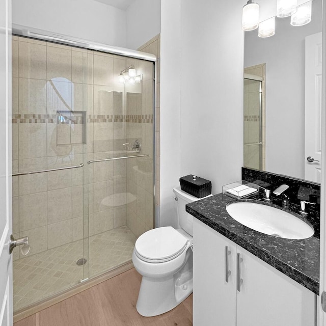 bathroom with toilet, a shower with door, and wood-type flooring