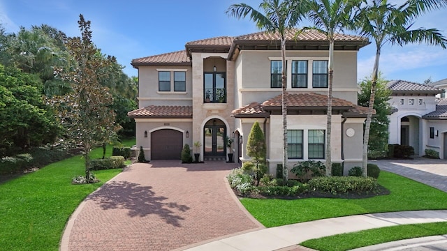 mediterranean / spanish house featuring french doors, a tiled roof, stucco siding, decorative driveway, and a front yard