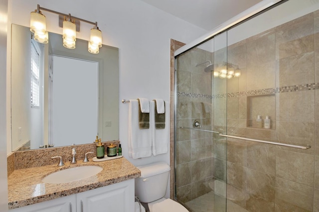 bathroom with toilet, vanity, and a shower with shower door