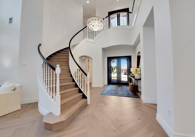 entrance foyer with a chandelier, french doors, light parquet flooring, and a high ceiling