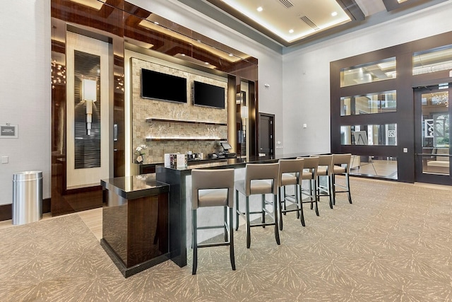 bar with light floors, visible vents, indoor wet bar, and a towering ceiling