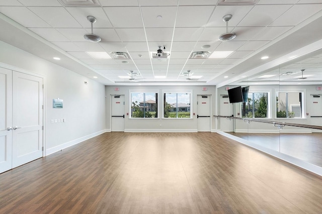 exercise room with hardwood / wood-style floors, a wealth of natural light, and a paneled ceiling