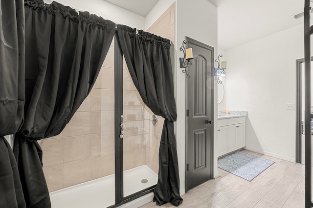 bathroom with a tile shower, wood-type flooring, and vanity