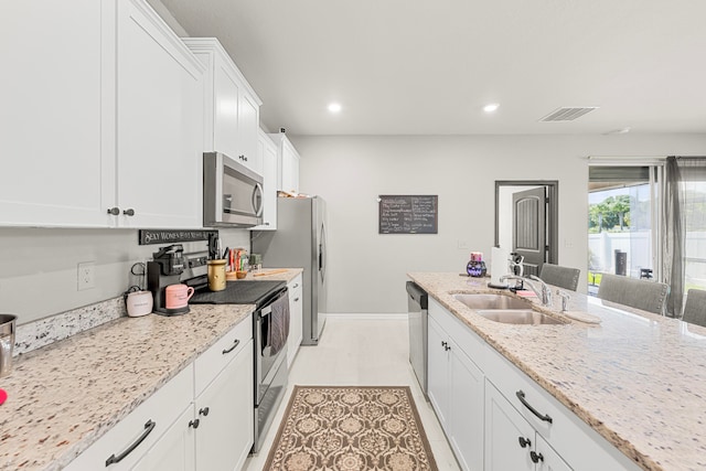 kitchen with light stone countertops, stainless steel appliances, sink, and white cabinetry