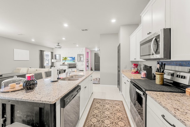 kitchen with a kitchen island with sink, appliances with stainless steel finishes, sink, and white cabinetry