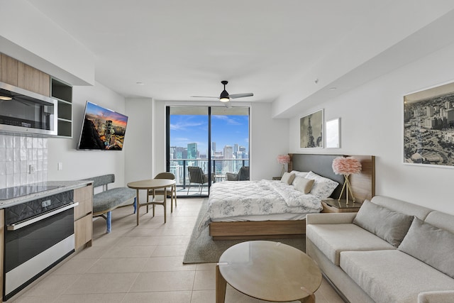 bedroom featuring access to outside, a wall of windows, light tile patterned floors, and ceiling fan