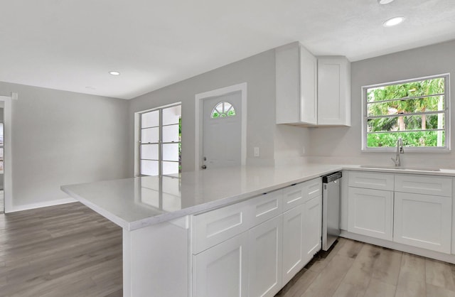 kitchen featuring light hardwood / wood-style flooring, white cabinets, kitchen peninsula, and sink