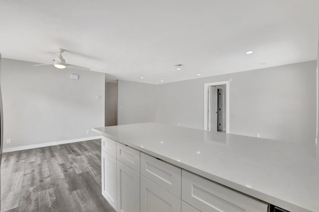 kitchen featuring ceiling fan, light stone counters, light hardwood / wood-style floors, and white cabinetry