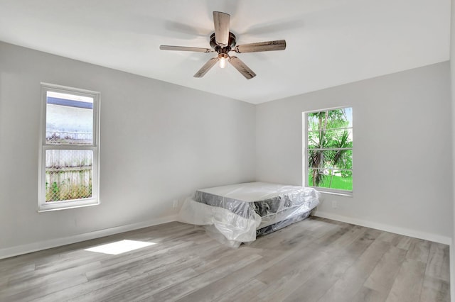 unfurnished bedroom featuring ceiling fan, light wood-type flooring, and multiple windows