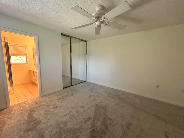 unfurnished bedroom featuring a textured ceiling, light colored carpet, a closet, and ceiling fan