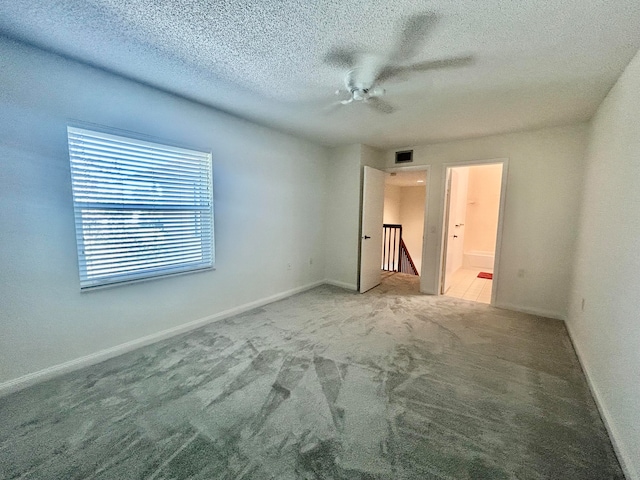 spare room featuring carpet flooring, ceiling fan, and a textured ceiling