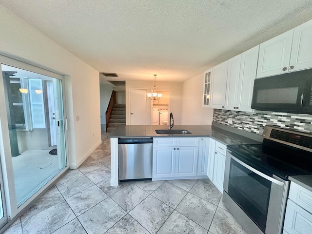 kitchen with pendant lighting, kitchen peninsula, sink, appliances with stainless steel finishes, and white cabinetry