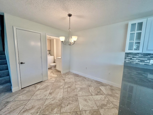 unfurnished dining area with a notable chandelier, washer / dryer, and a textured ceiling