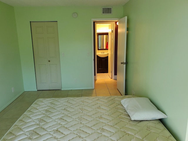 unfurnished bedroom with connected bathroom, sink, and light tile patterned floors