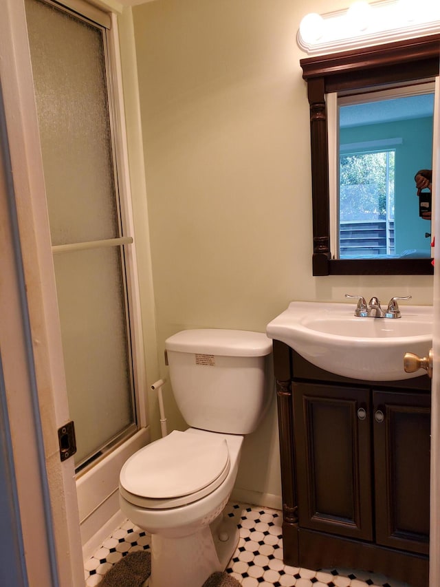 full bathroom featuring shower / bath combination with glass door, tile patterned flooring, vanity, and toilet