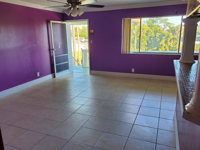 tiled empty room featuring ornamental molding, ceiling fan, plenty of natural light, and ornate columns