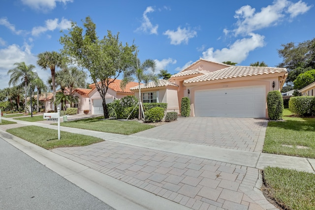 mediterranean / spanish home featuring a garage and a front lawn