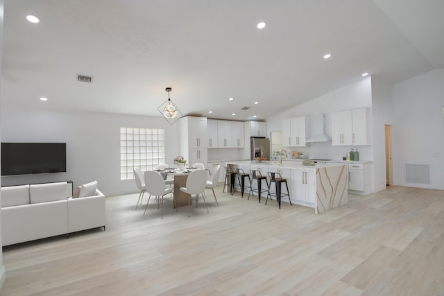 dining area with sink, light hardwood / wood-style floors, and vaulted ceiling