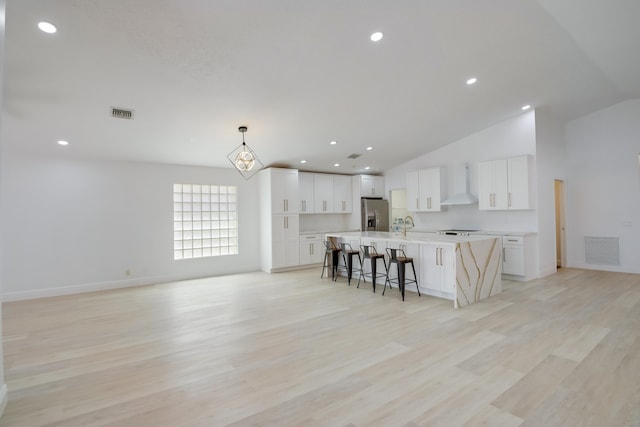 spare room featuring ceiling fan with notable chandelier, light wood-type flooring, and lofted ceiling